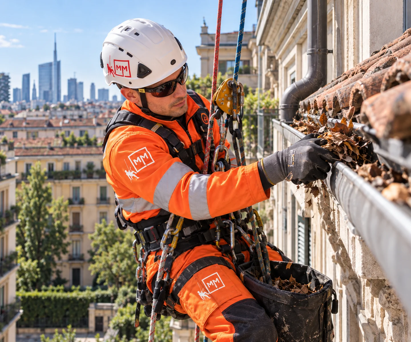 Operatore MM Solutions in fune durante la pulizia di una grondaia su edificio urbano